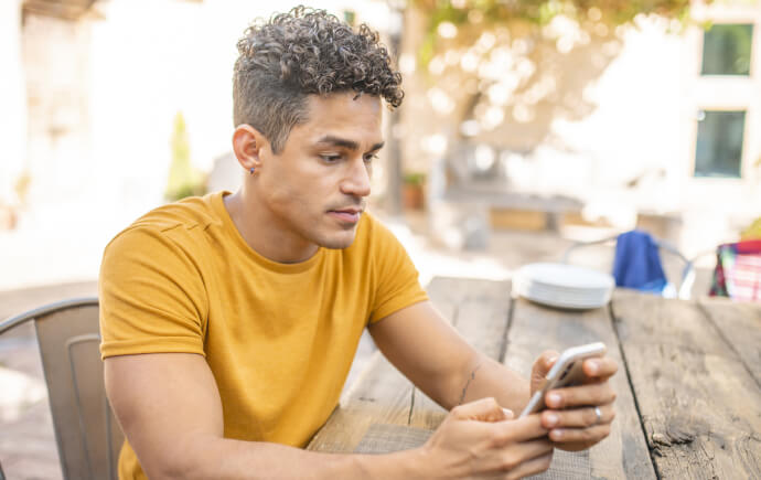 Young man using phone in outdoor restaurant