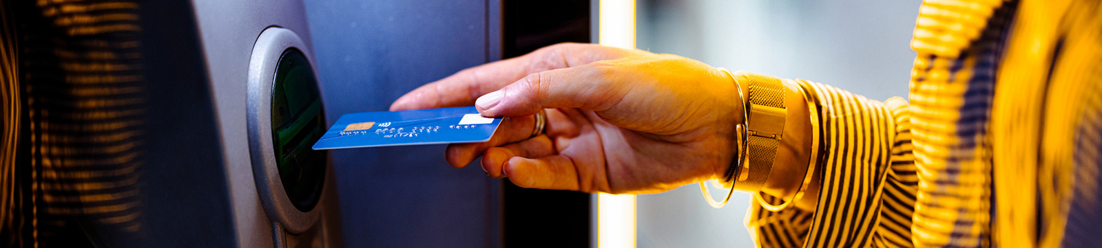 Close up of woman using debit card at ATM